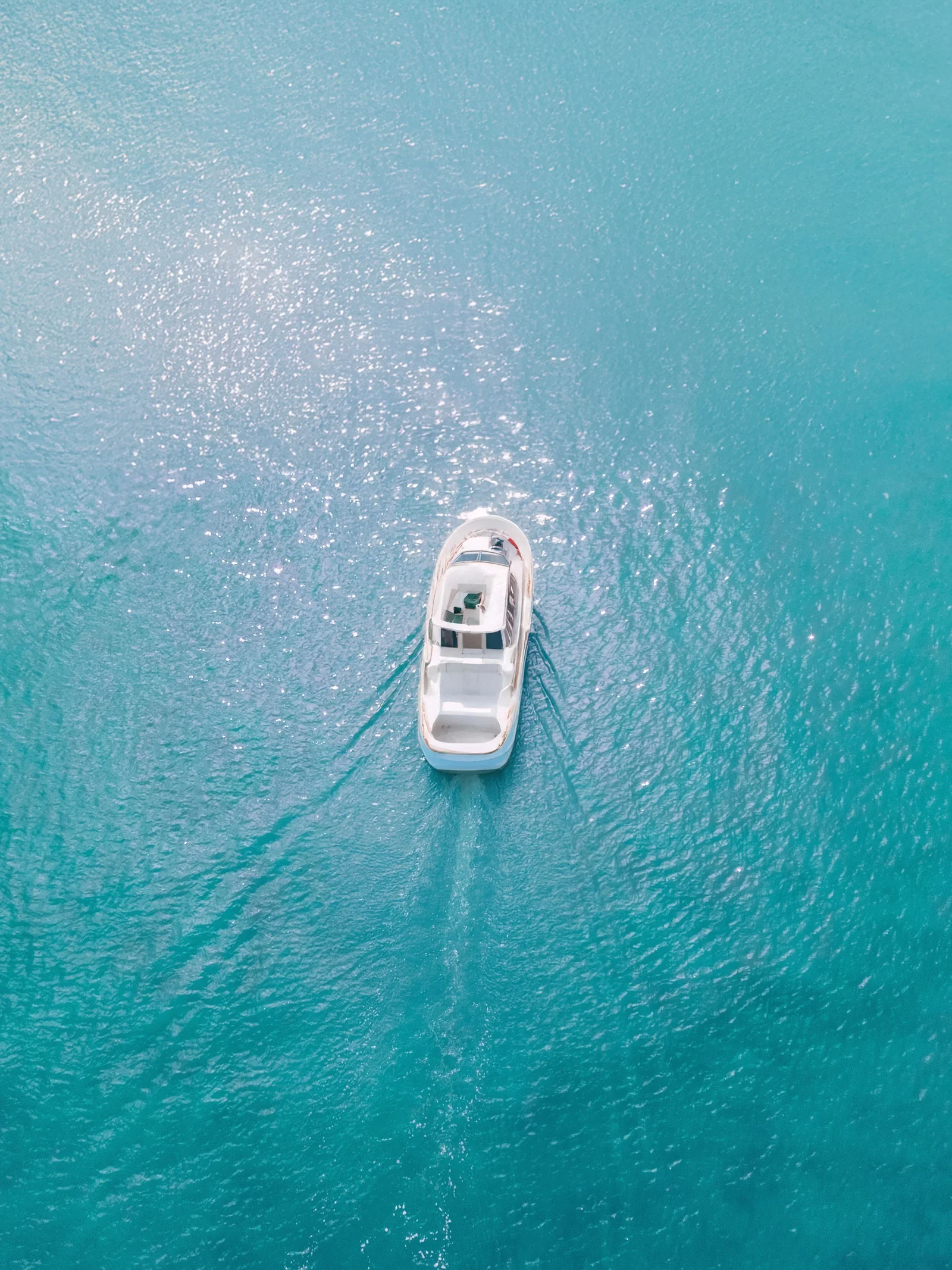 A white yacht cruising through clear sunlit turquoise water